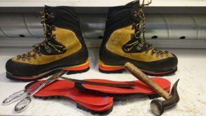 chaussure de haute montagne avec des outils de cordonnerie, ciseaux, marteaux, tranchet et semelles vibram toutes neuves
