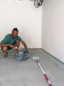 Yvan, artisan de la clinique du chausson et du matos en train de peindre le sol de l'atelier
